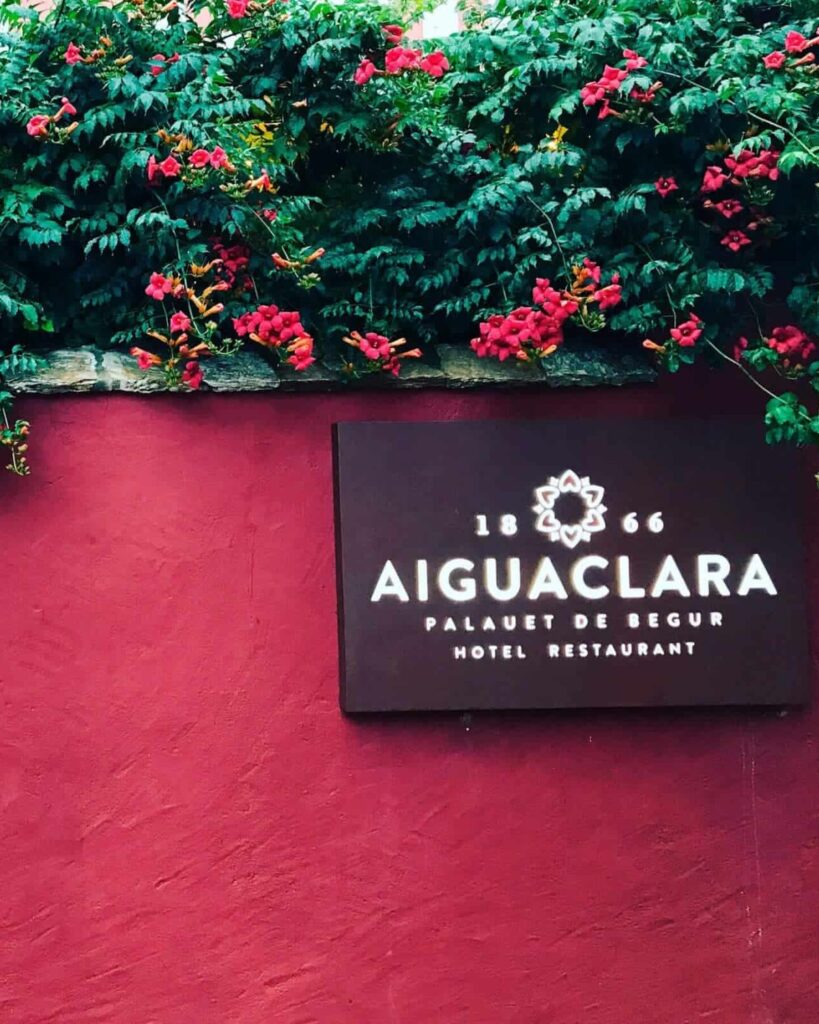 Placa de Aiguaclara, Palauet de Begur, sobre el muro rojo con buganvilla