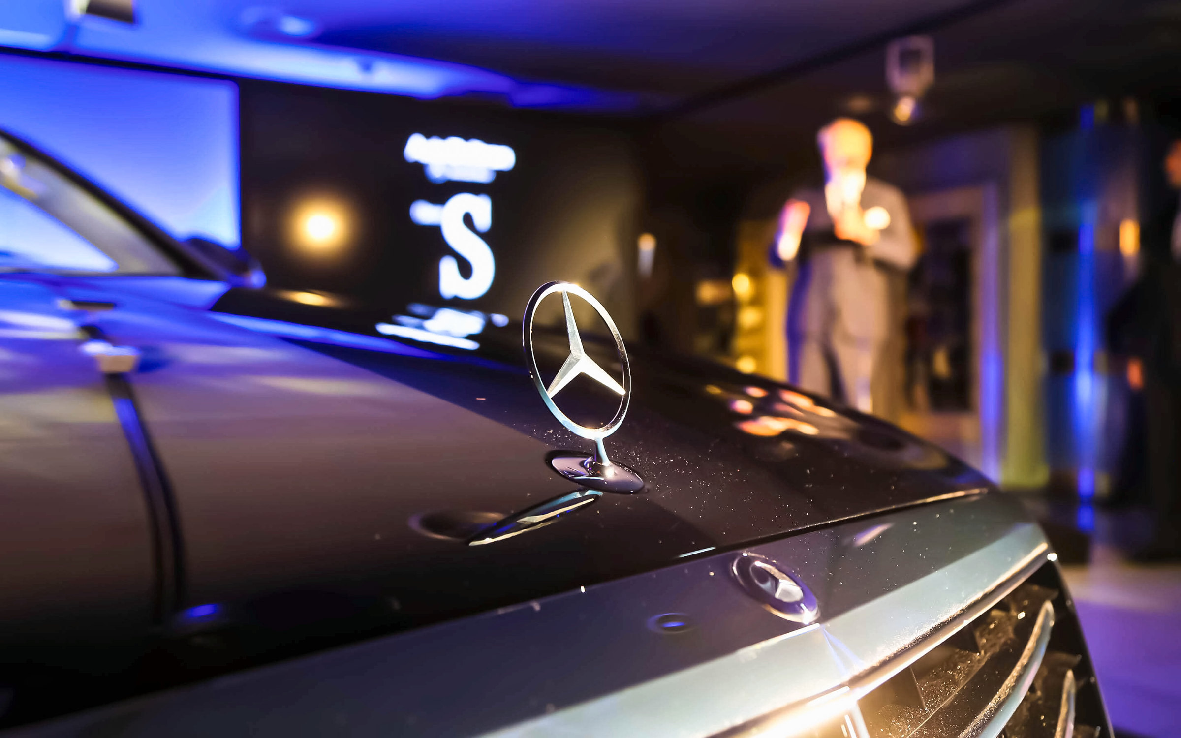 La estrella de Mercedes-Benz sobre el capó de la nueva Clase S, con la sala del concesionario de Sant Gervasi al fondo