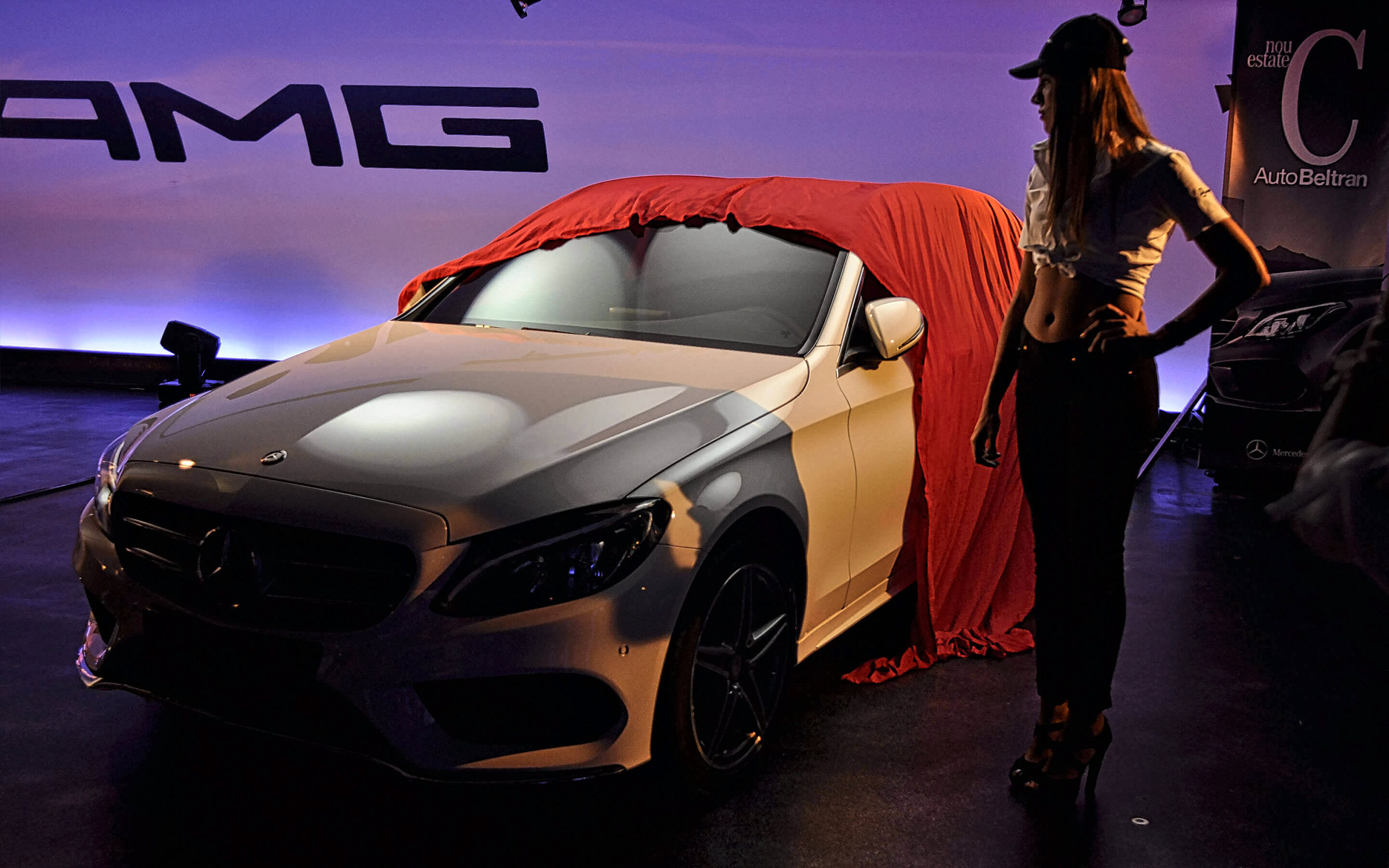 Un Mercedes-Benz descapotable al que retiran la funda roja, bajo el rótulo de AMG, en la inauguración del Performance Center