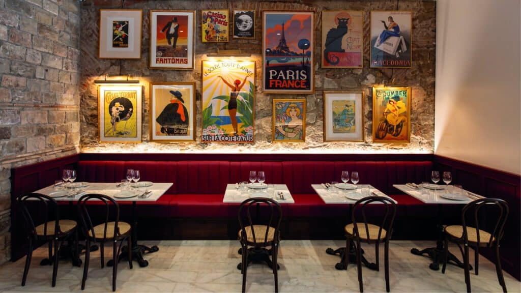 Comedor de Café Pablo con banqueta granate y una pared de carteles de época