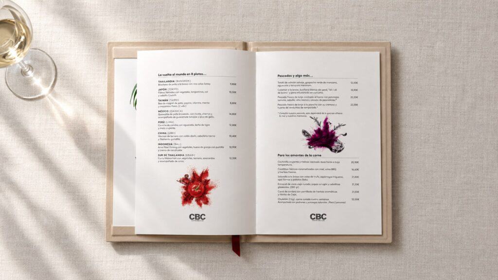 Recreación: carta de CBC abierta por «La vuelta al mundo en 8 platos», junto a una copa de vino blanco