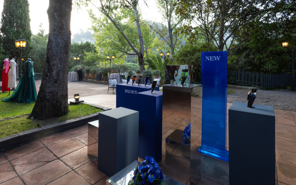 El podio azul de Bad Boy en el jardín, con maniquíes vestidos de Carolina Herrera al fondo