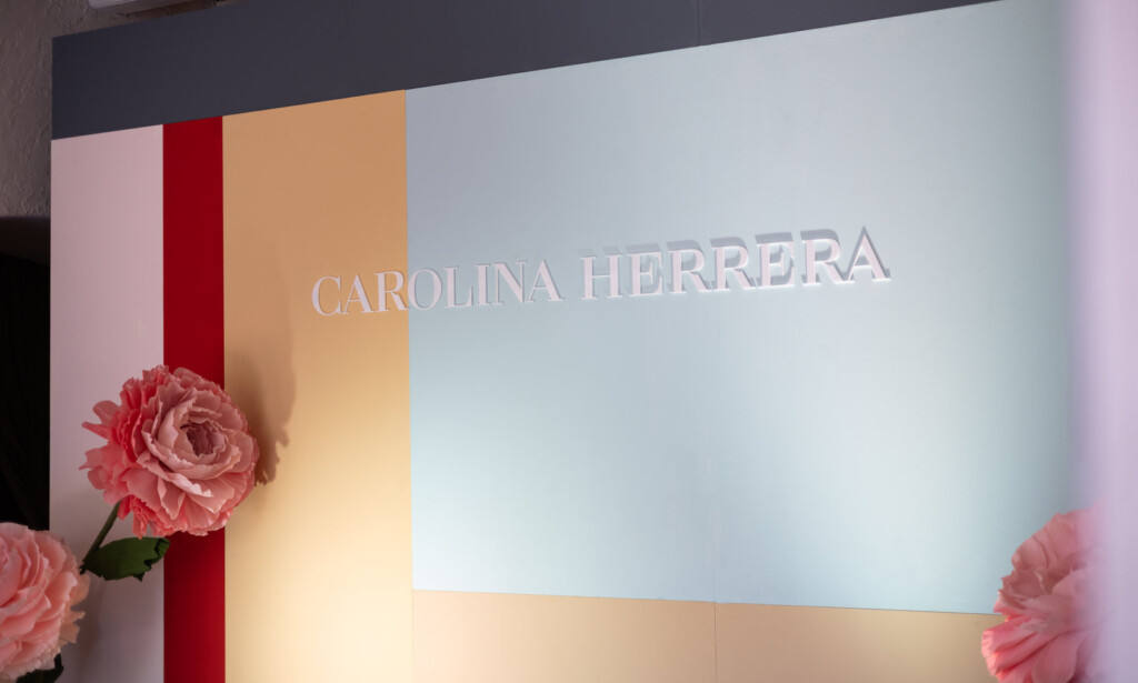 El photocall con el nombre de Carolina Herrera, bandas de color y flores de papel