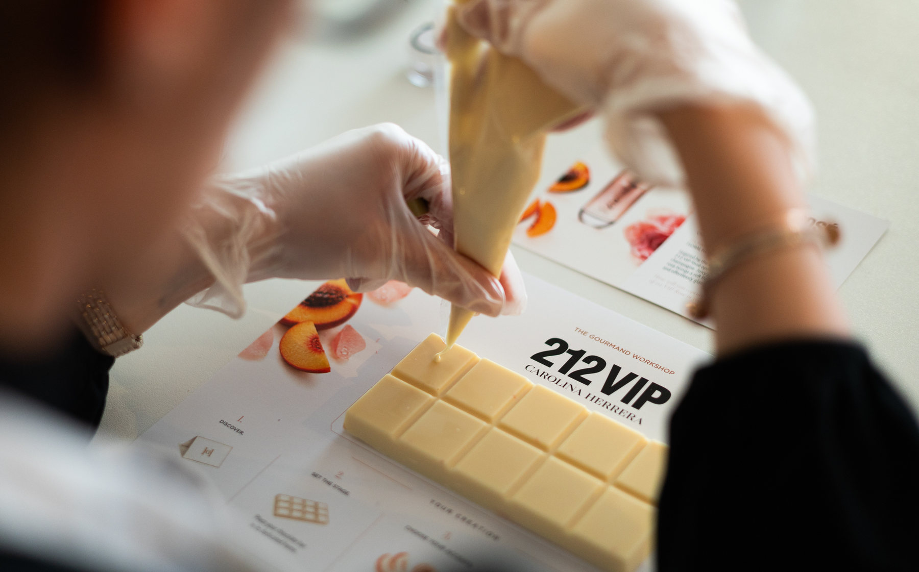Un participante decora una tableta de chocolate blanco de 212 VIP en el taller Gourmand Activity