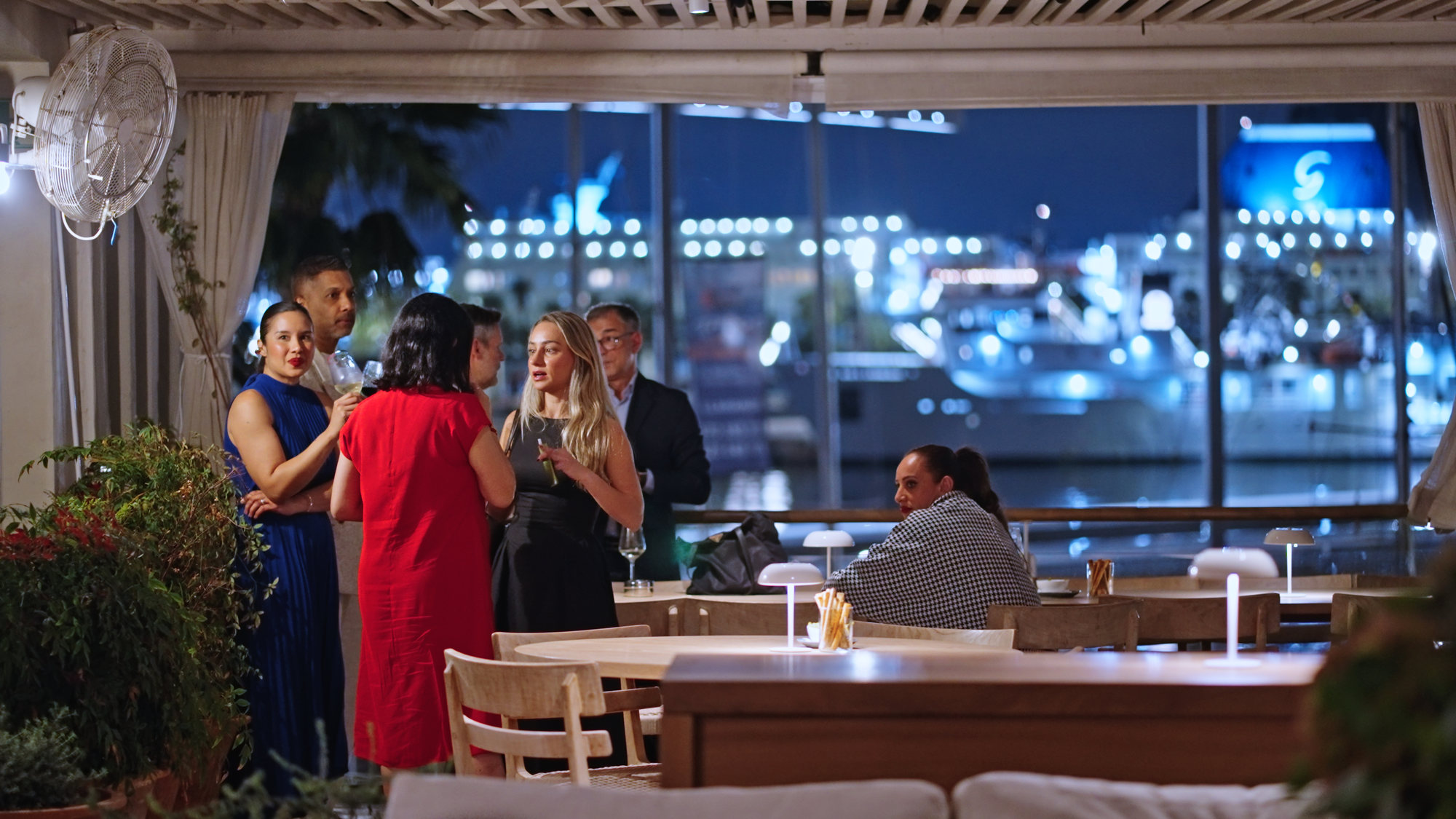 Invitados en la Soirée Herrera, en el restaurante Fiskebar, con el puerto de Barcelona iluminado detrás
