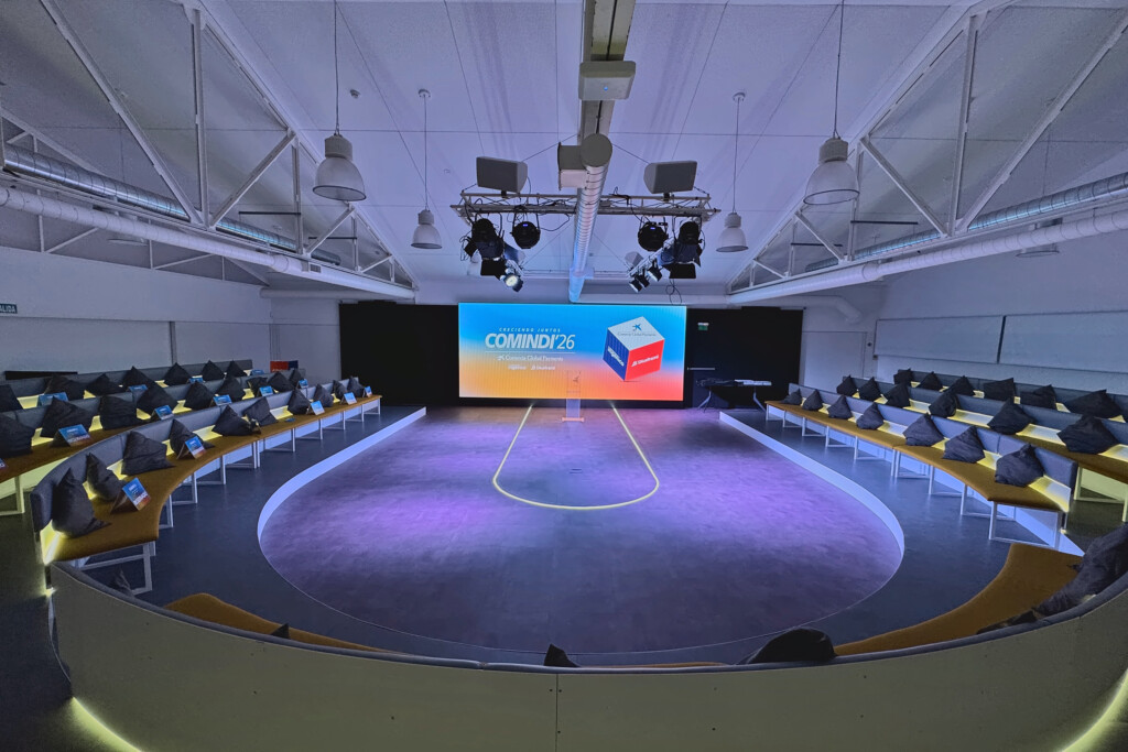 The COMINDI'26 auditorium set and ready, with the oval tiered seating, the line of light and the event screen at the back
