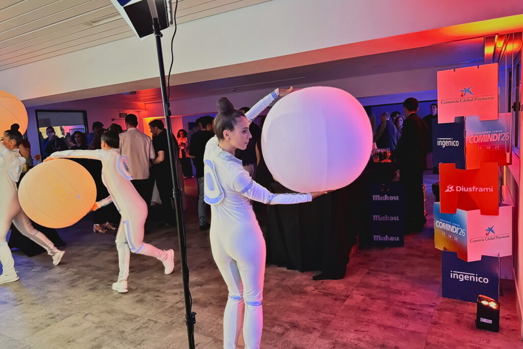 Dancers with spheres of light among the COMINDI'26 guests, beside the brand cubes