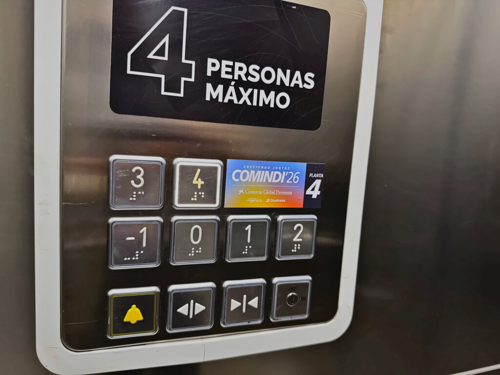 The lift button panel with the COMINDI'26 vinyl marking the event floor