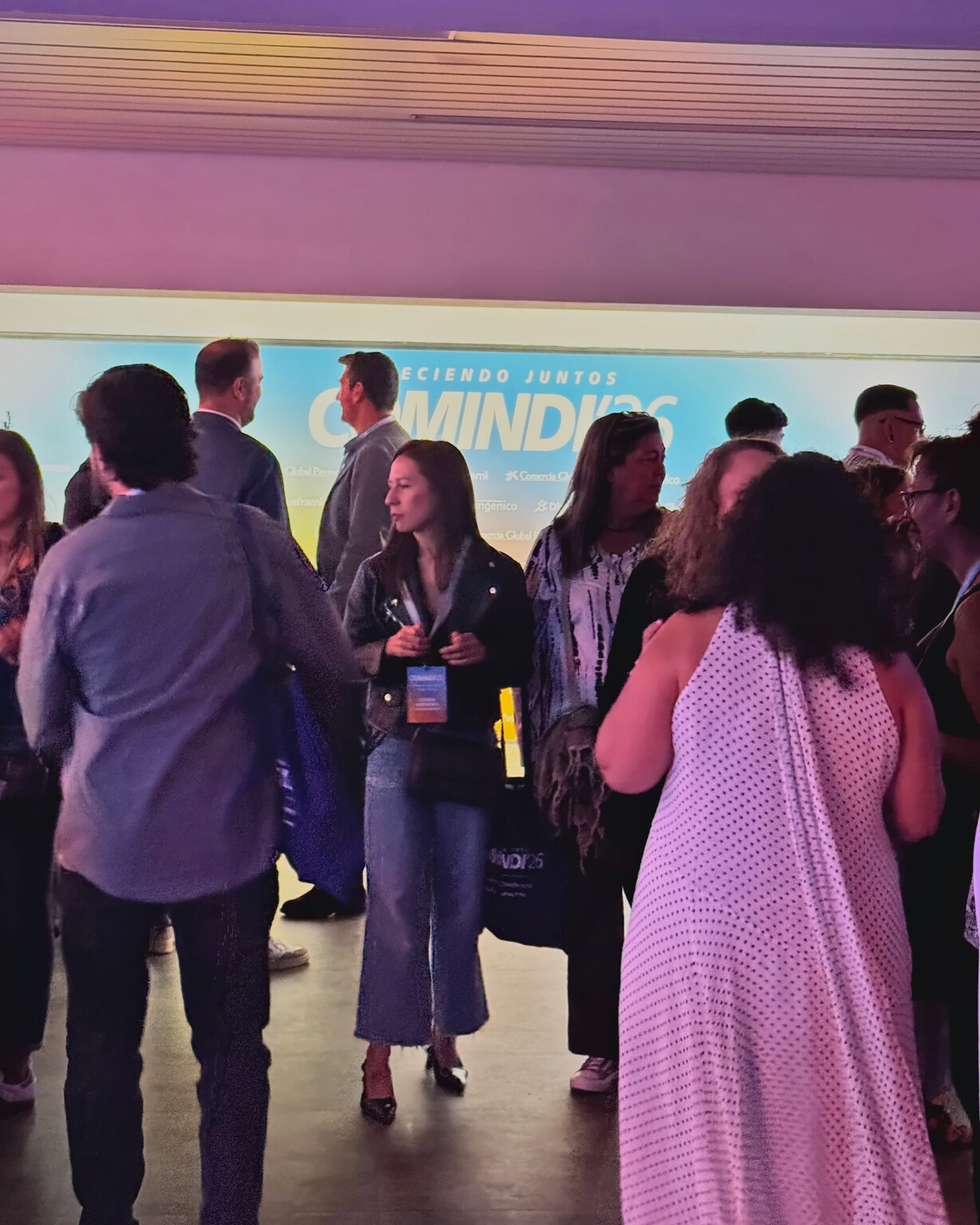 Guests wearing their passes at the COMINDI'26 drinks reception, in front of the event photocall