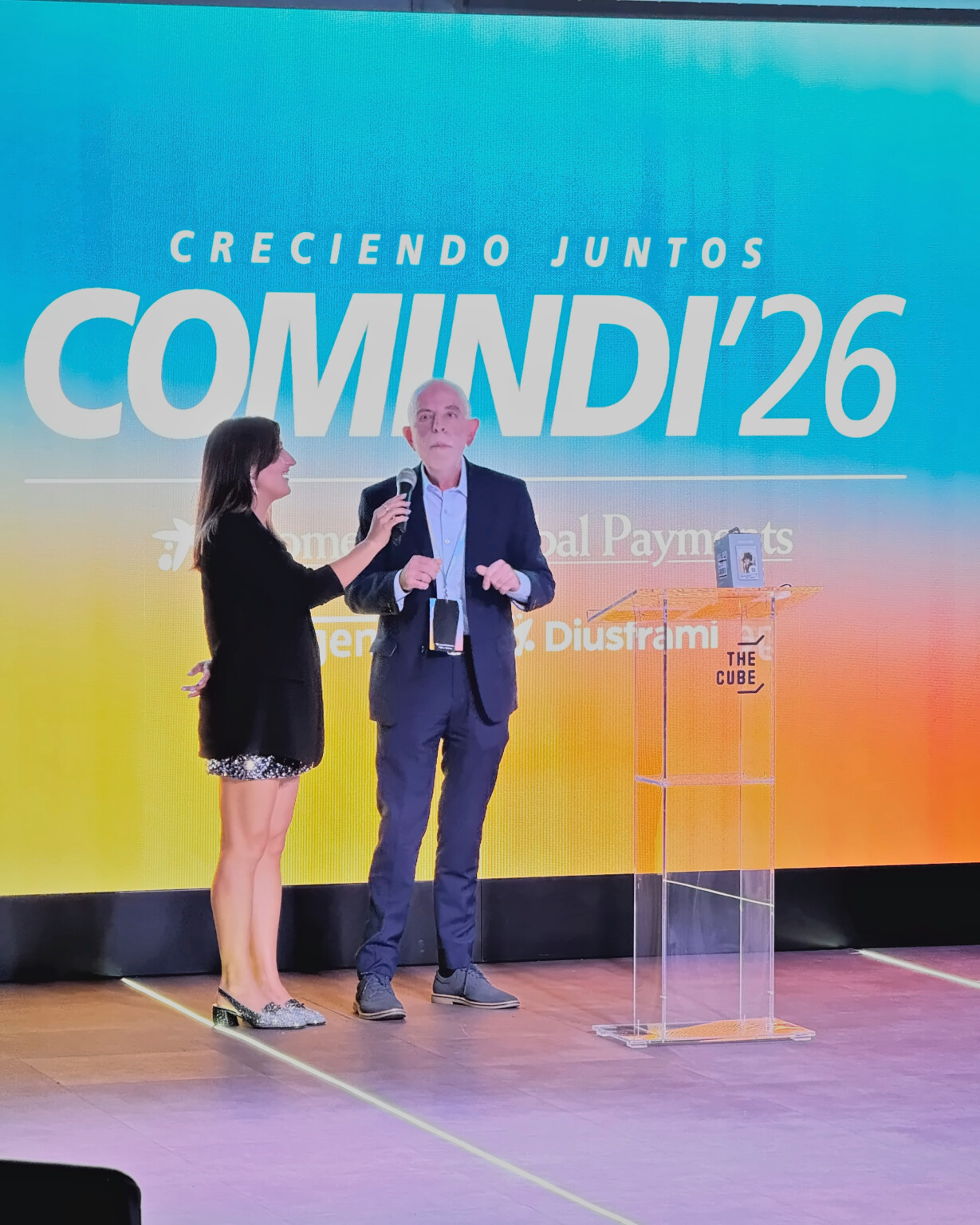 Presenters on the COMINDI'26 stage in front of the “Creciendo juntos” (Growing together) screen