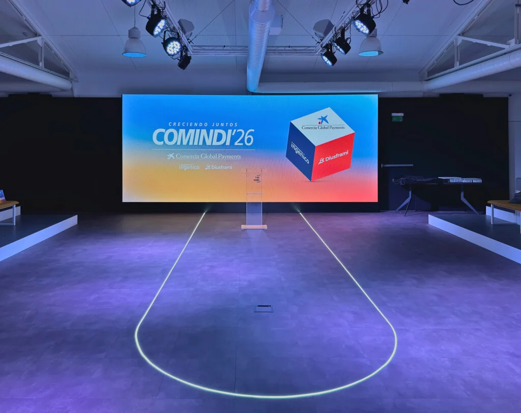 The COMINDI'26 stage in Madrid, with the large “Creciendo juntos” (Growing together) screen, the lectern and the line of light on the floor