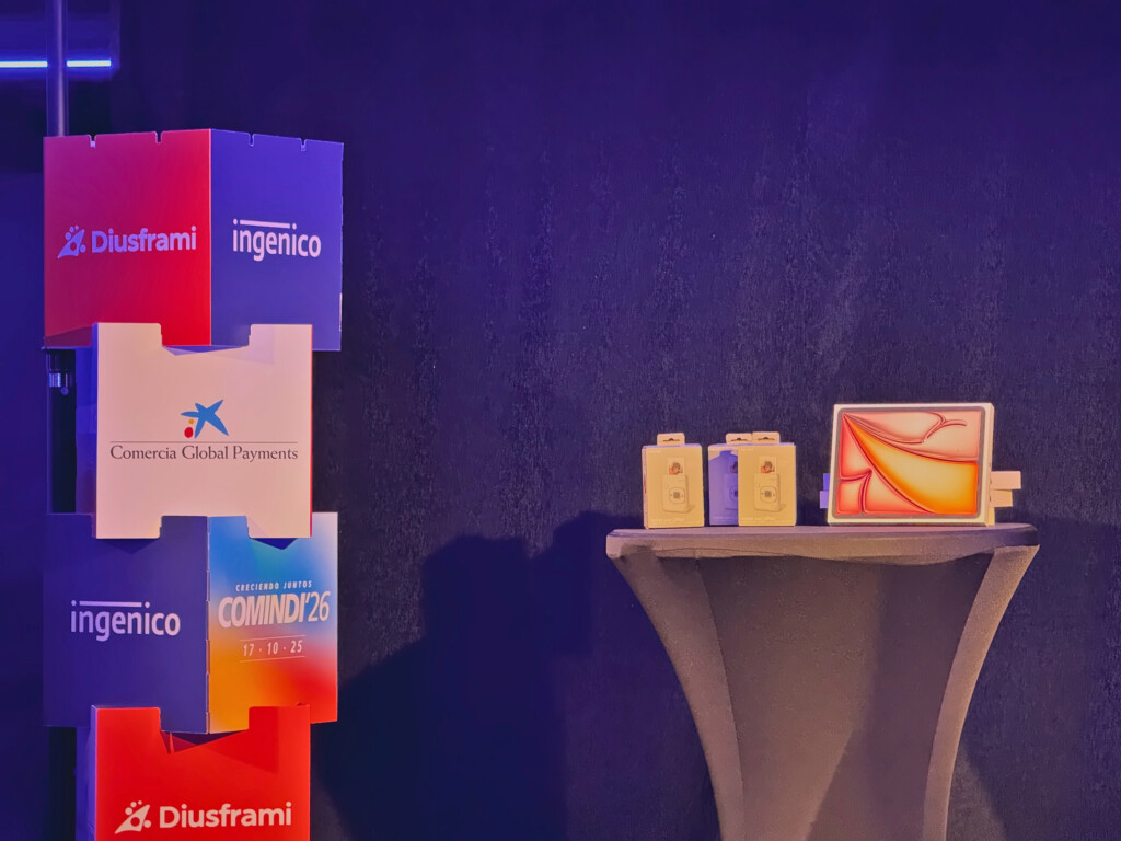The COMINDI'26 awards table beside a column of cubes bearing the event brands