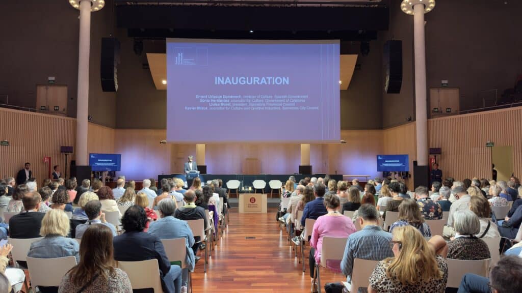 Pantalla de inauguración y público en el auditorio del encuentro