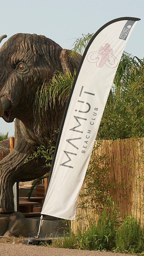 El mamut de la entrada de Mamut Beach Club, junto a una banderola