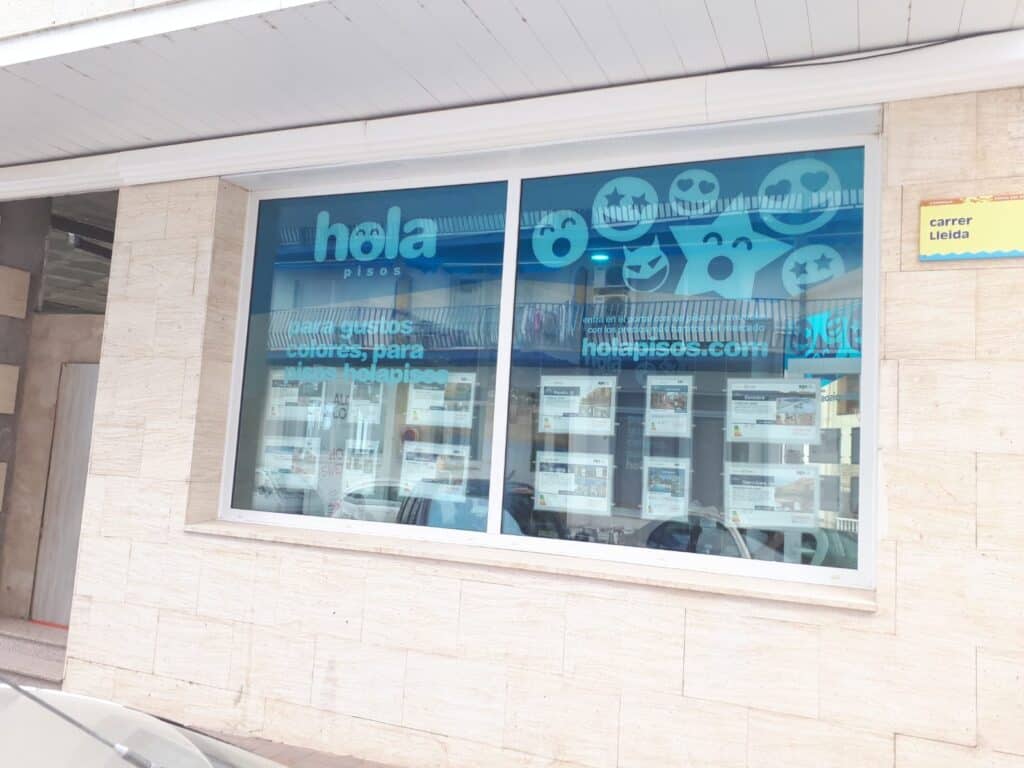 Oficina de Hola Pisos a pie de calle con los vinilos de la marca en el escaparate