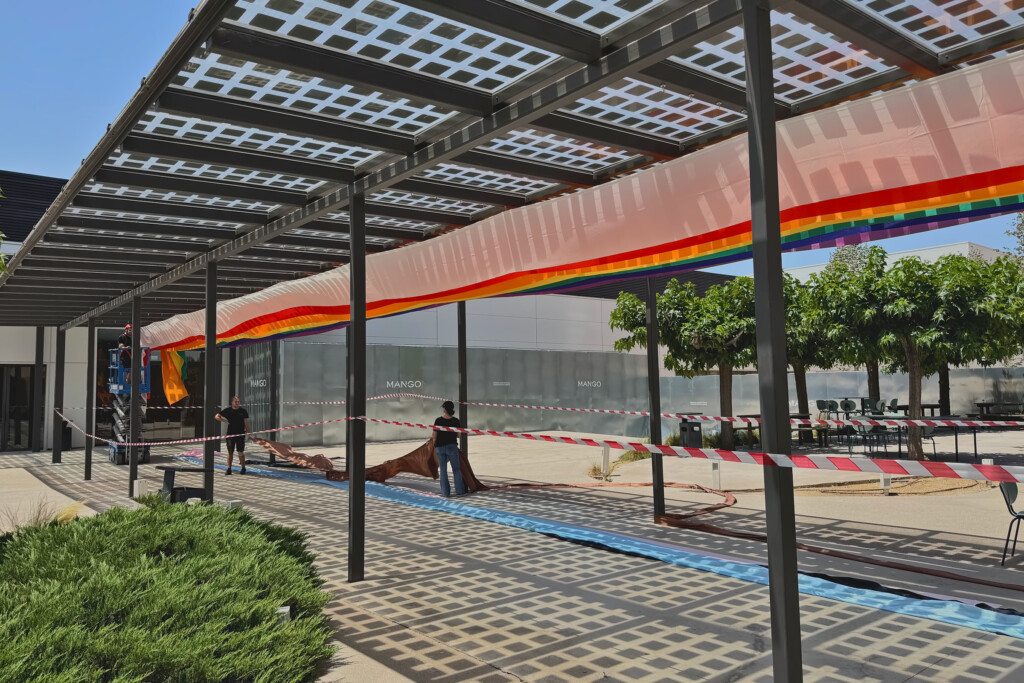 Pérgola solar de la sede central de Mango con una tela del Orgullo a lo largo de toda su longitud durante el montaje