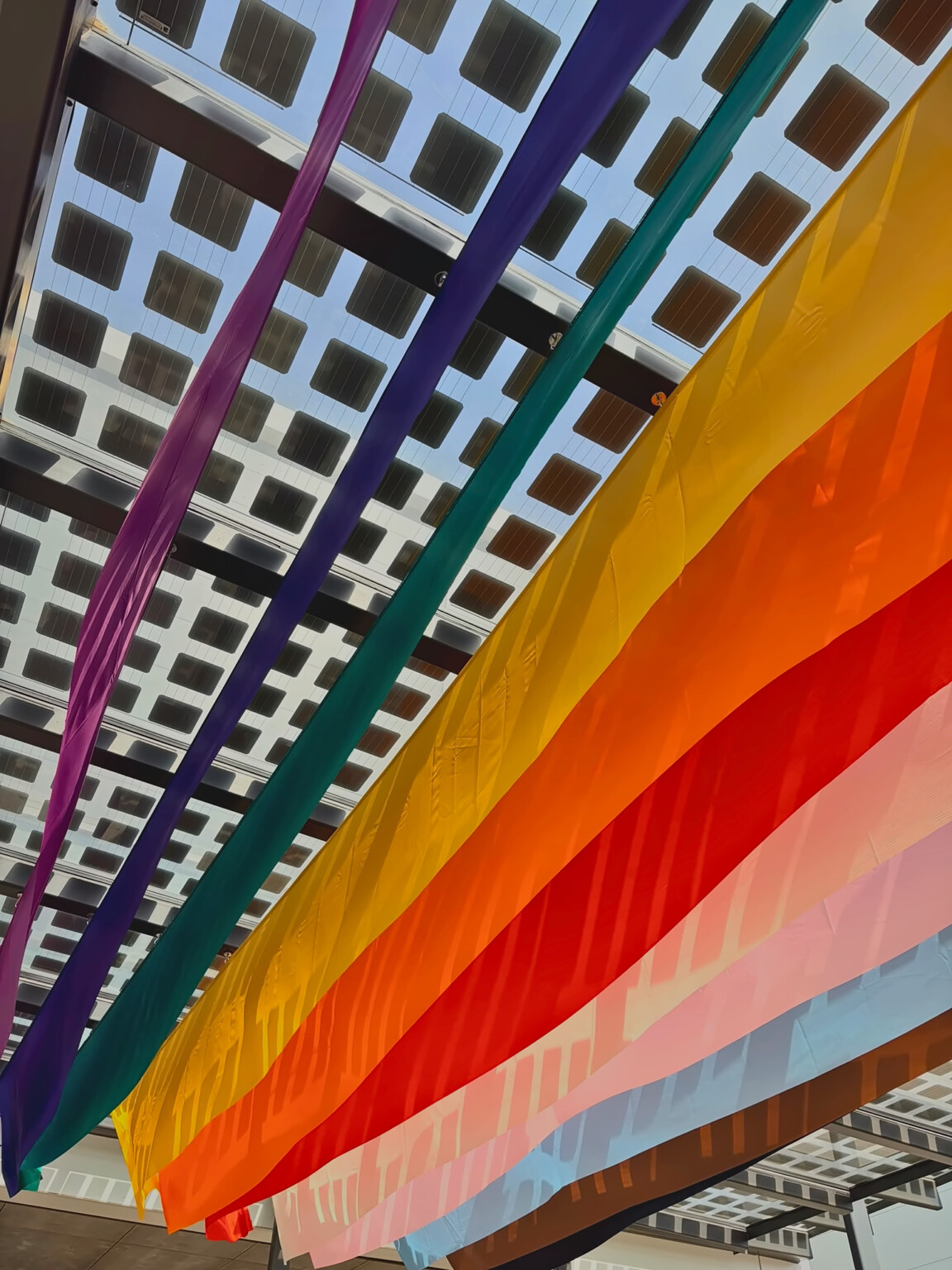 Detalle de las telas del Orgullo sujetas a la estructura de la pérgola solar