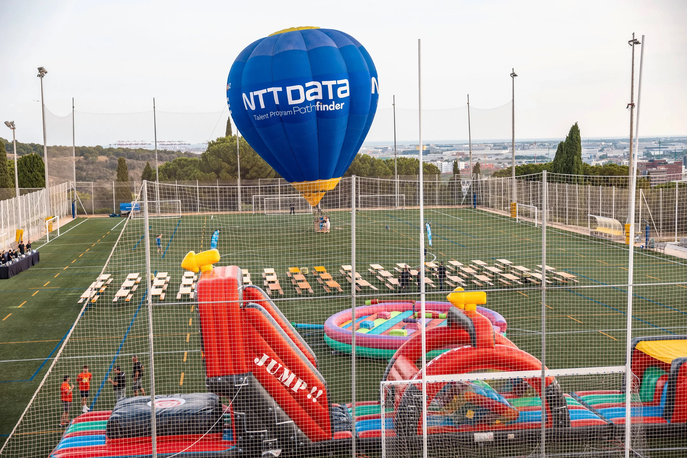 Globo cautivo de NTT DATA sobre el campo con hinchables y juegos