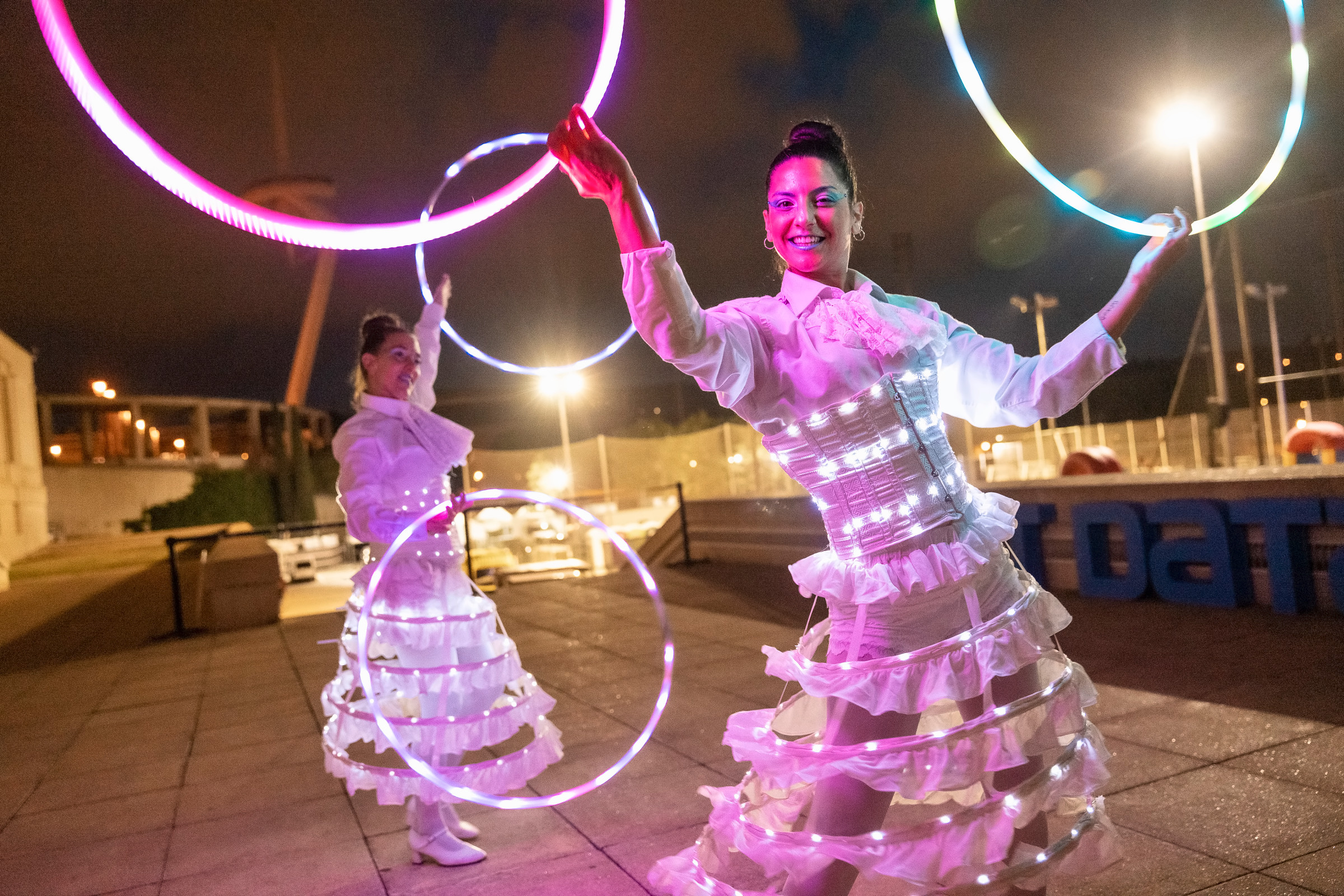 Artistas con aros de luz entre el público por la noche