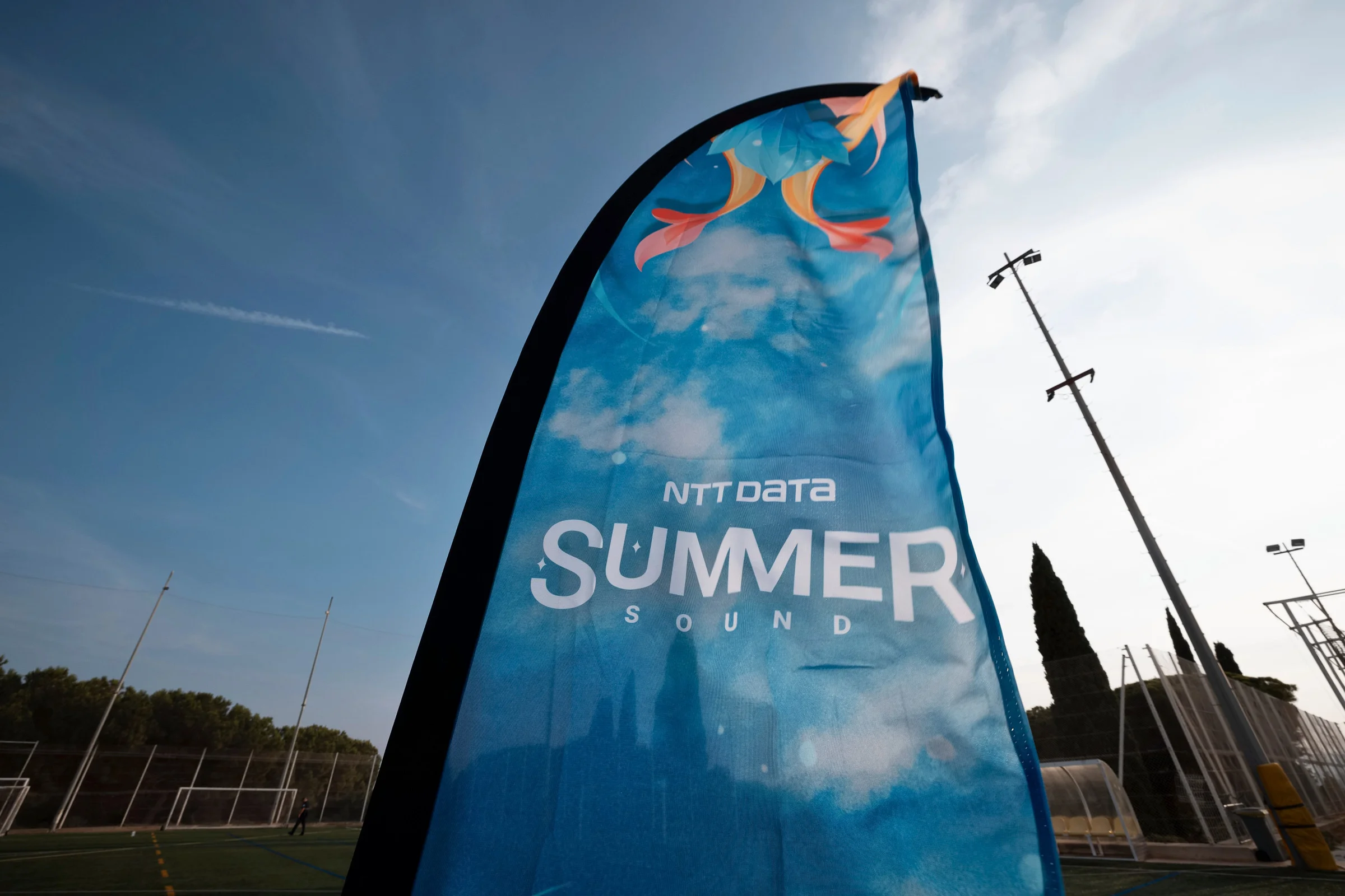 Bandera del Summer Sound de NTT DATA frente al cielo de la tarde en Montjuïc