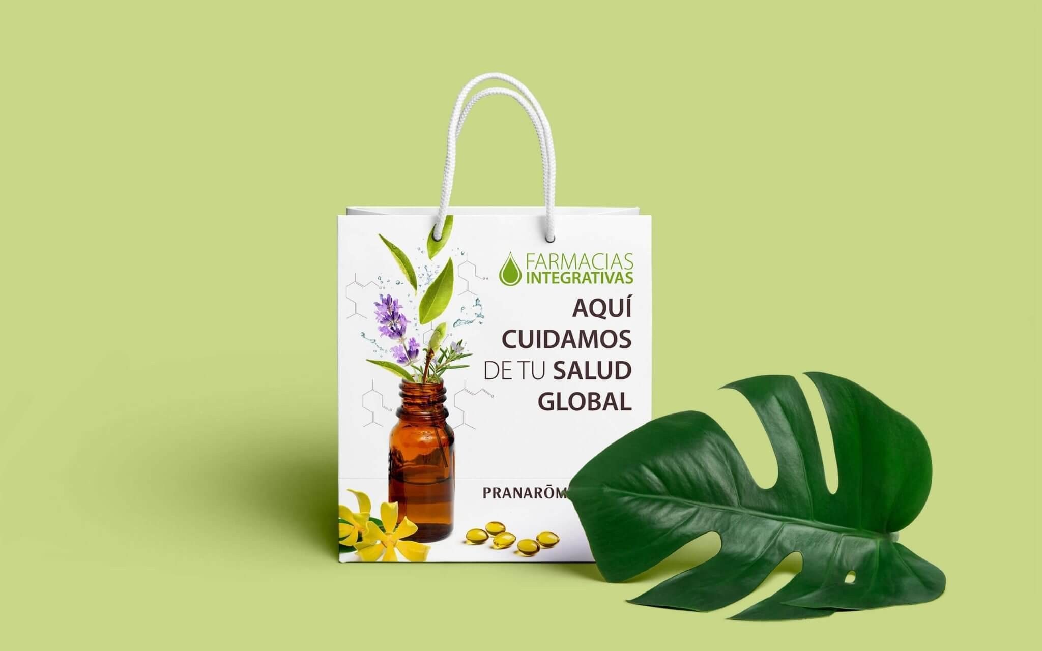 Bolsa de papel de Farmacias Integrativas junto a una hoja de monstera