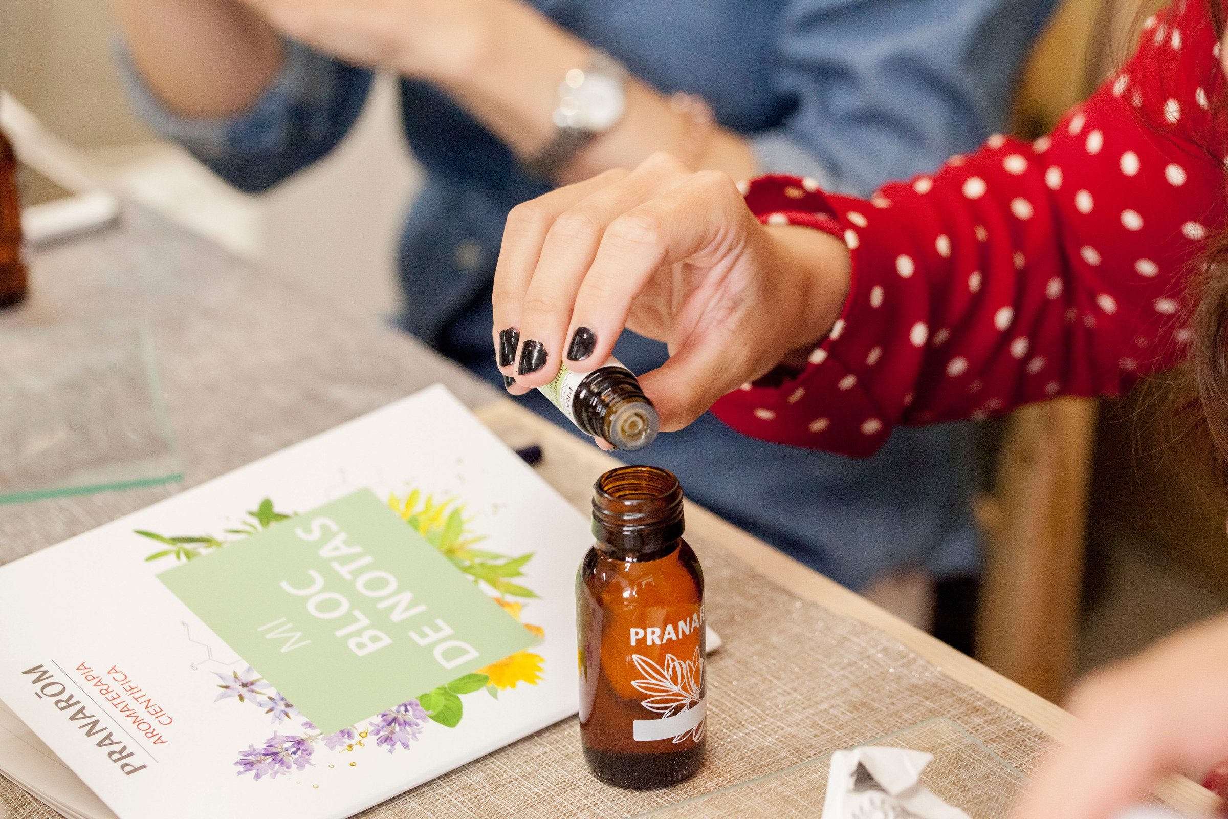 Taller de aromaterapia de Pranarôm: una mano vierte aceite esencial en un frasco