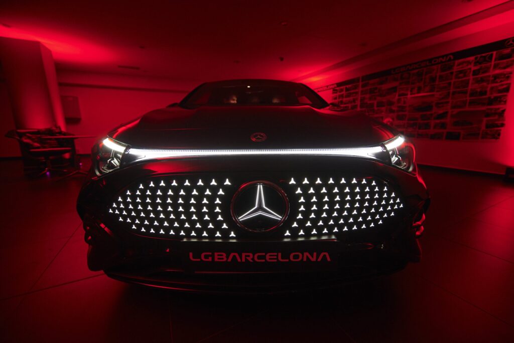 Frontal iluminado del nuevo Mercedes-Benz CLA con la placa de LG Barcelona, bajo la luz roja de la presentación