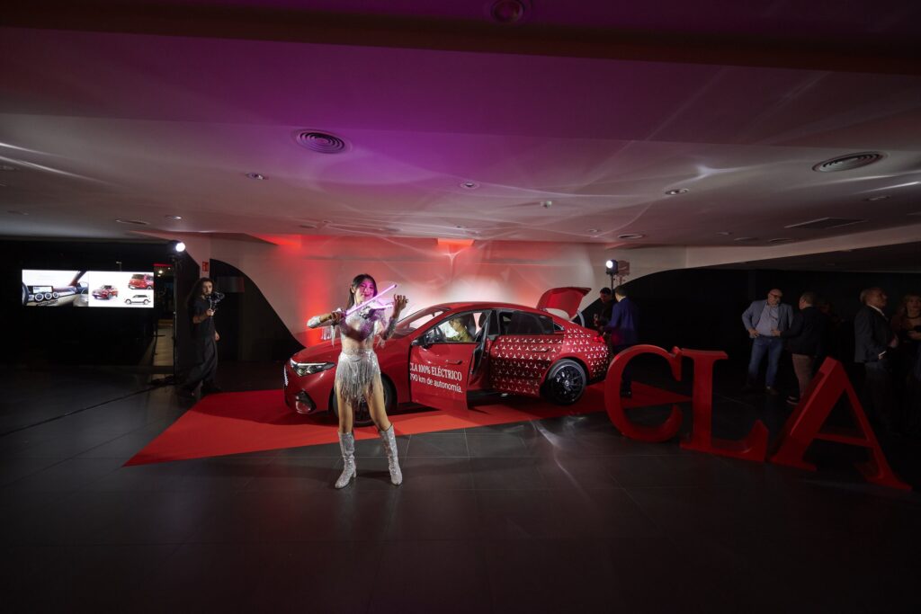 Violinista delante del nuevo Mercedes-Benz CLA con las puertas abiertas y las letras CLA en rojo
