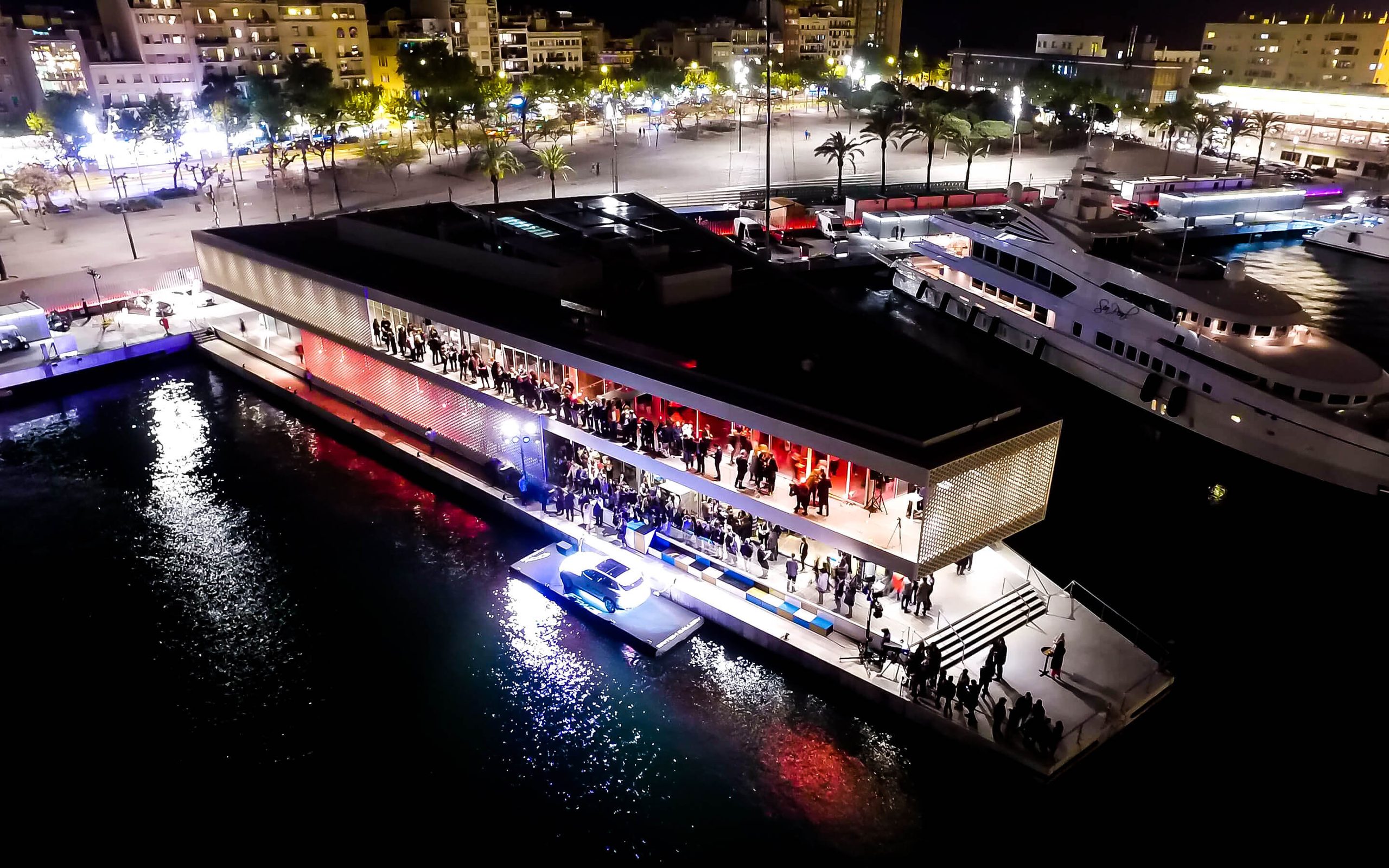La presentación del Jaguar F-Pace desde el aire: el One Ocean Club iluminado en el Port Vell, los invitados en las terrazas y el coche en su plataforma sobre el agua