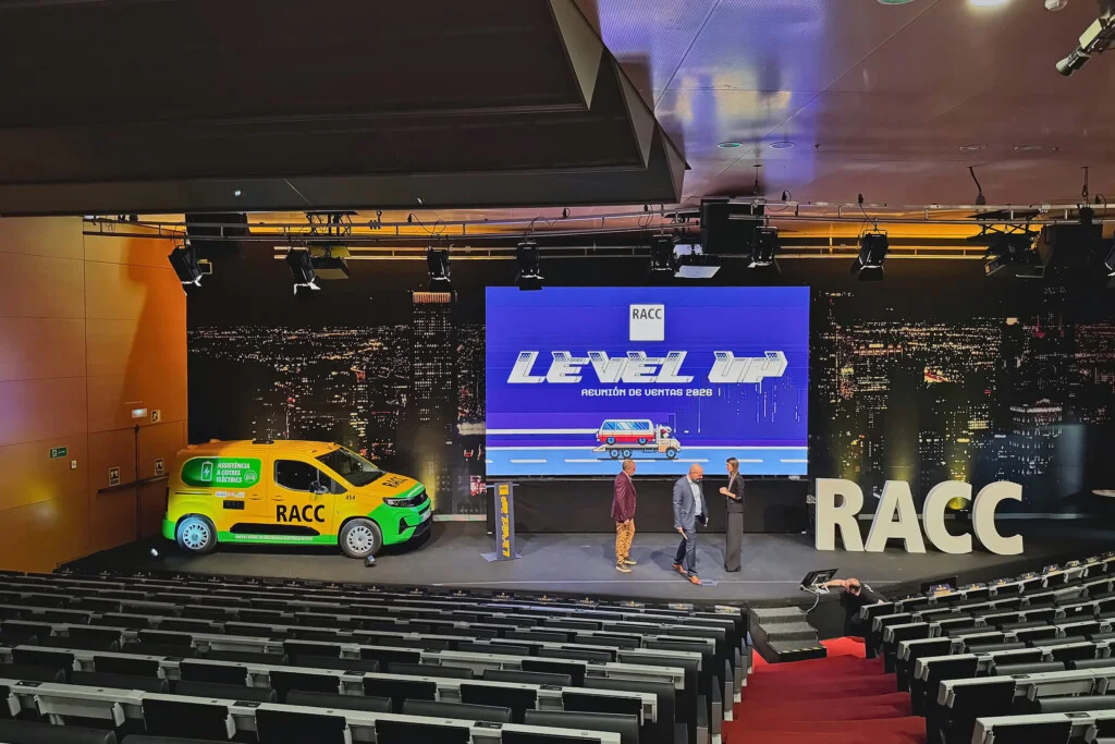 The auditorium set for RACC’s 2026 sales meeting, with “Level Up” on the big screen, a roadside assistance van and the RACC letters on stage