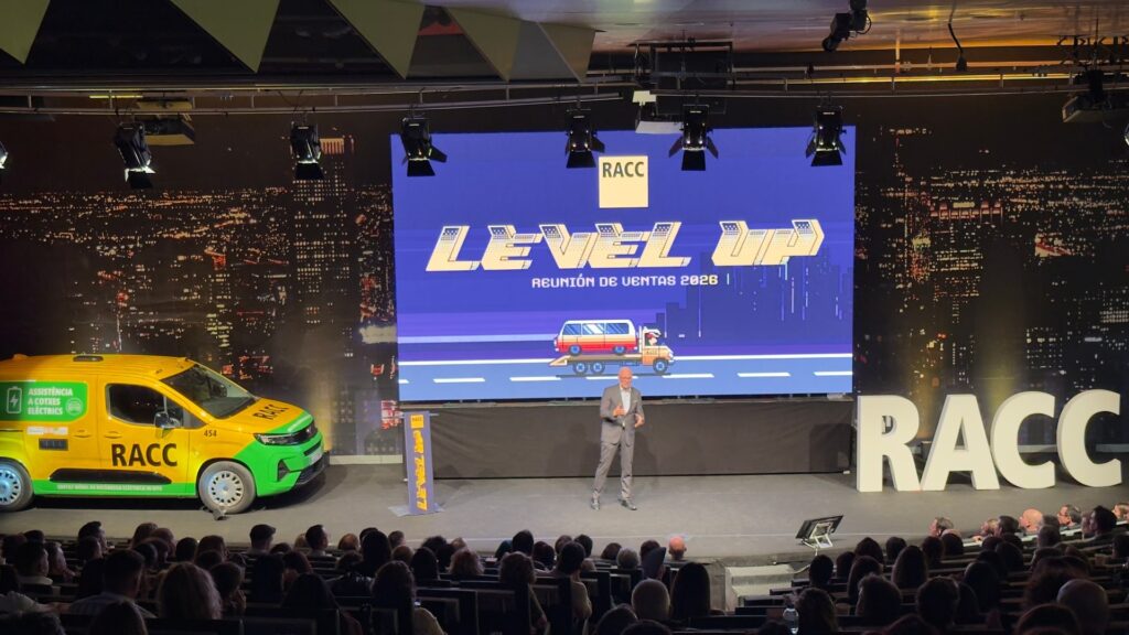 Escenario de la reunión de ventas 2026 del RACC con Level Up en la pantalla, una furgoneta de asistencia y las letras RACC