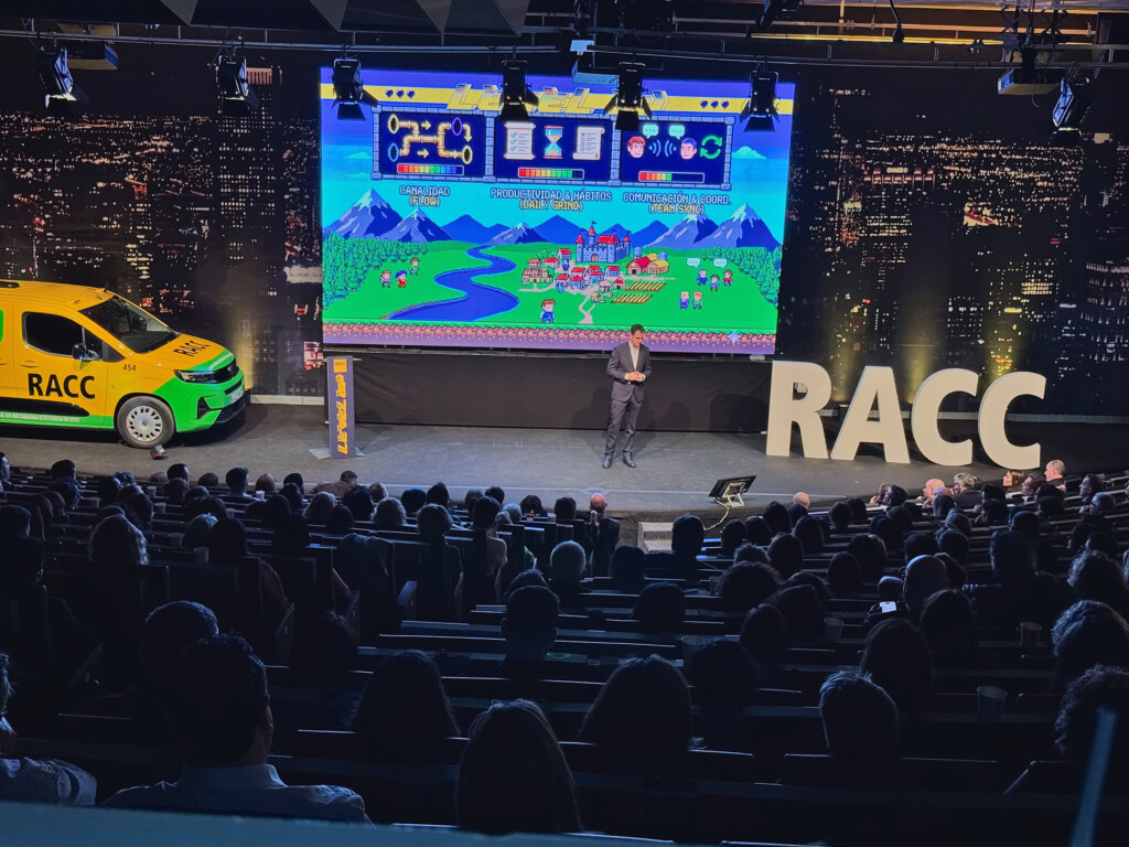 A speaker on stage in front of a pixelated level map during RACC’s 2026 sales meeting