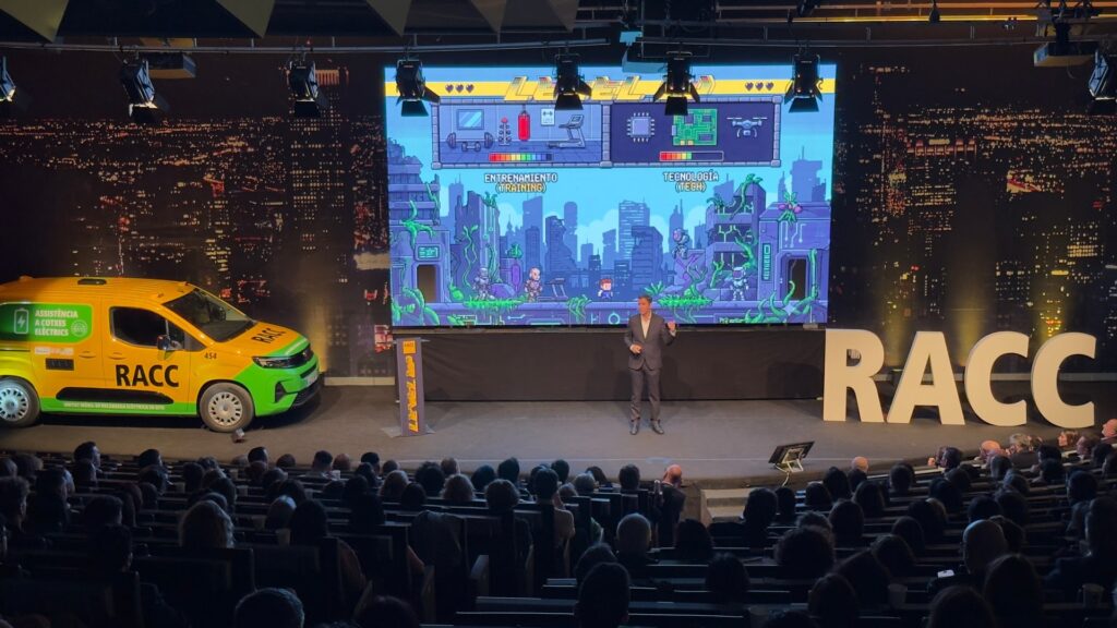 Ponente en el escenario del RACC ante la pantalla de Level Up con los niveles de entrenamiento y tecnología