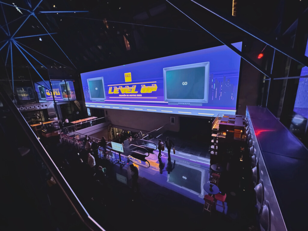 The glass-walled lobby at night, with the Level Up screen lit for RACC’s 2026 sales meeting