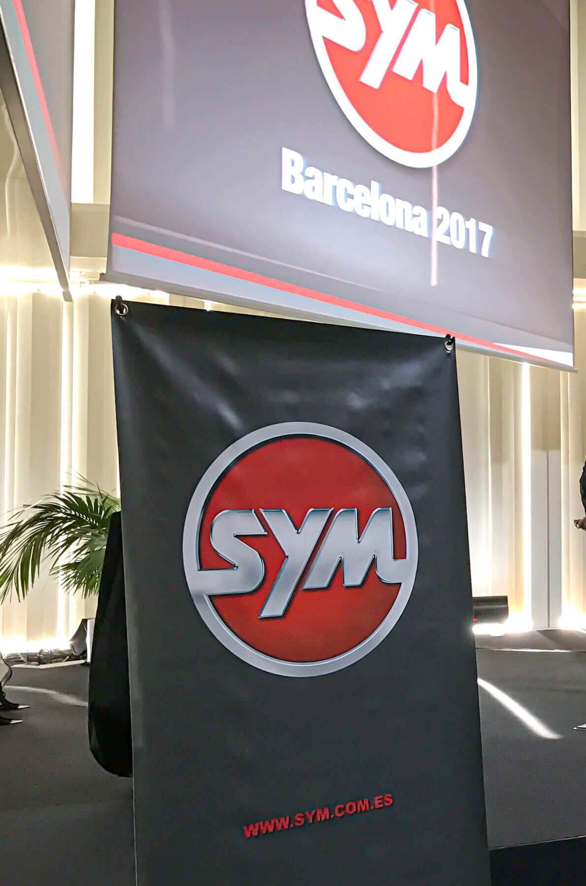 Escenario de la convención SYM Barcelona 2017, con la pantalla y el estandarte de la marca