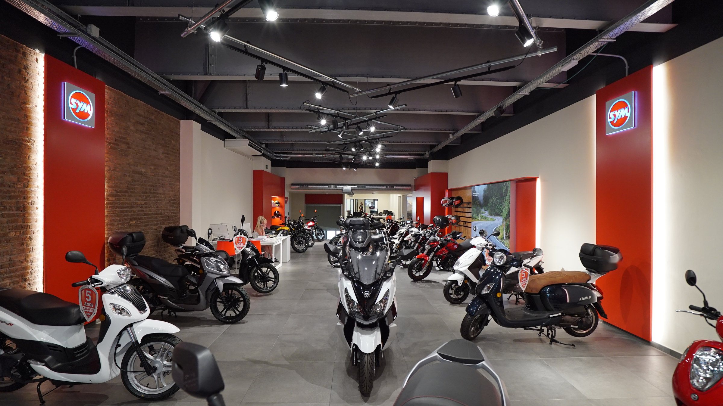 Tienda SYM de Motos Bordoy, con la gama expuesta entre paredes rojas