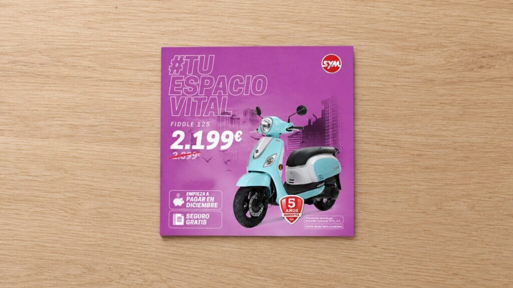 Recreación: folleto de la campaña «#TuEspacioVital» del Fiddle 125 de SYM sobre una mesa de madera