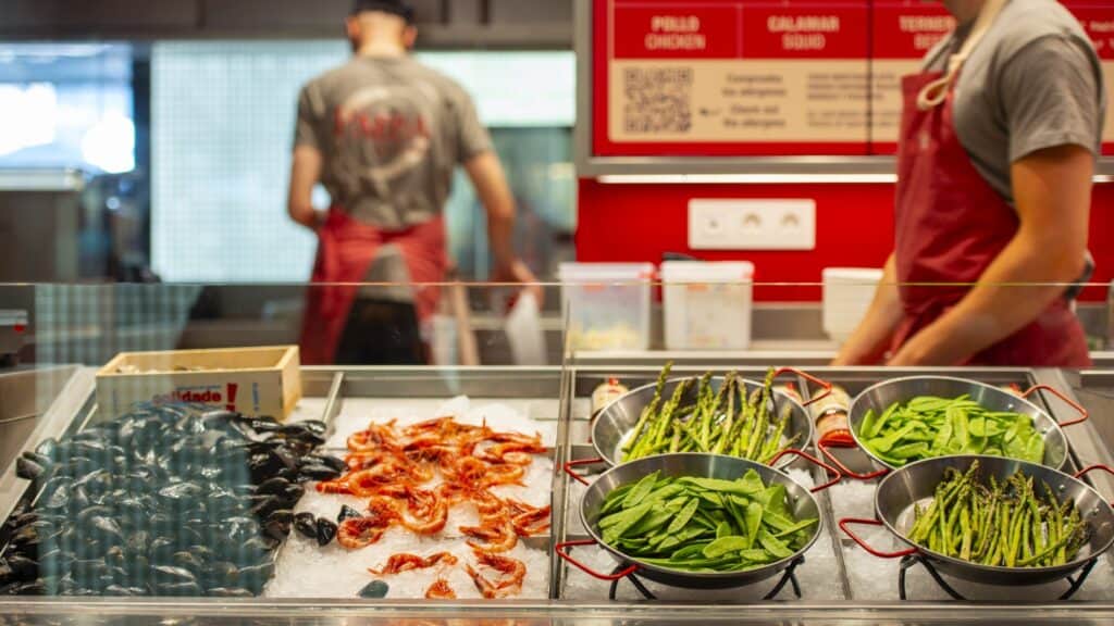 Mostrador de producto fresco de The Paella Factory con la carta y el código QR