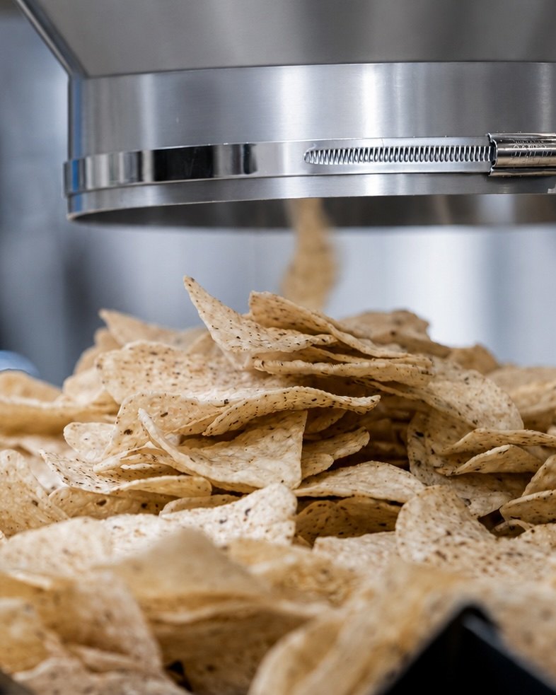Tortilla chips recién hechos bajo la tolva de la línea de producción