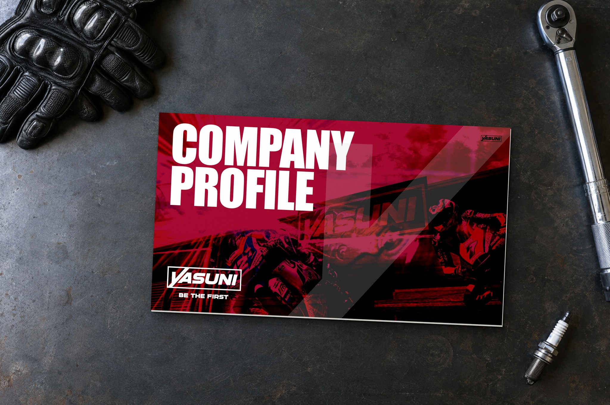 Recreación: el company profile de Yasuni impreso, sobre un banco de taller junto a unos guantes de competición