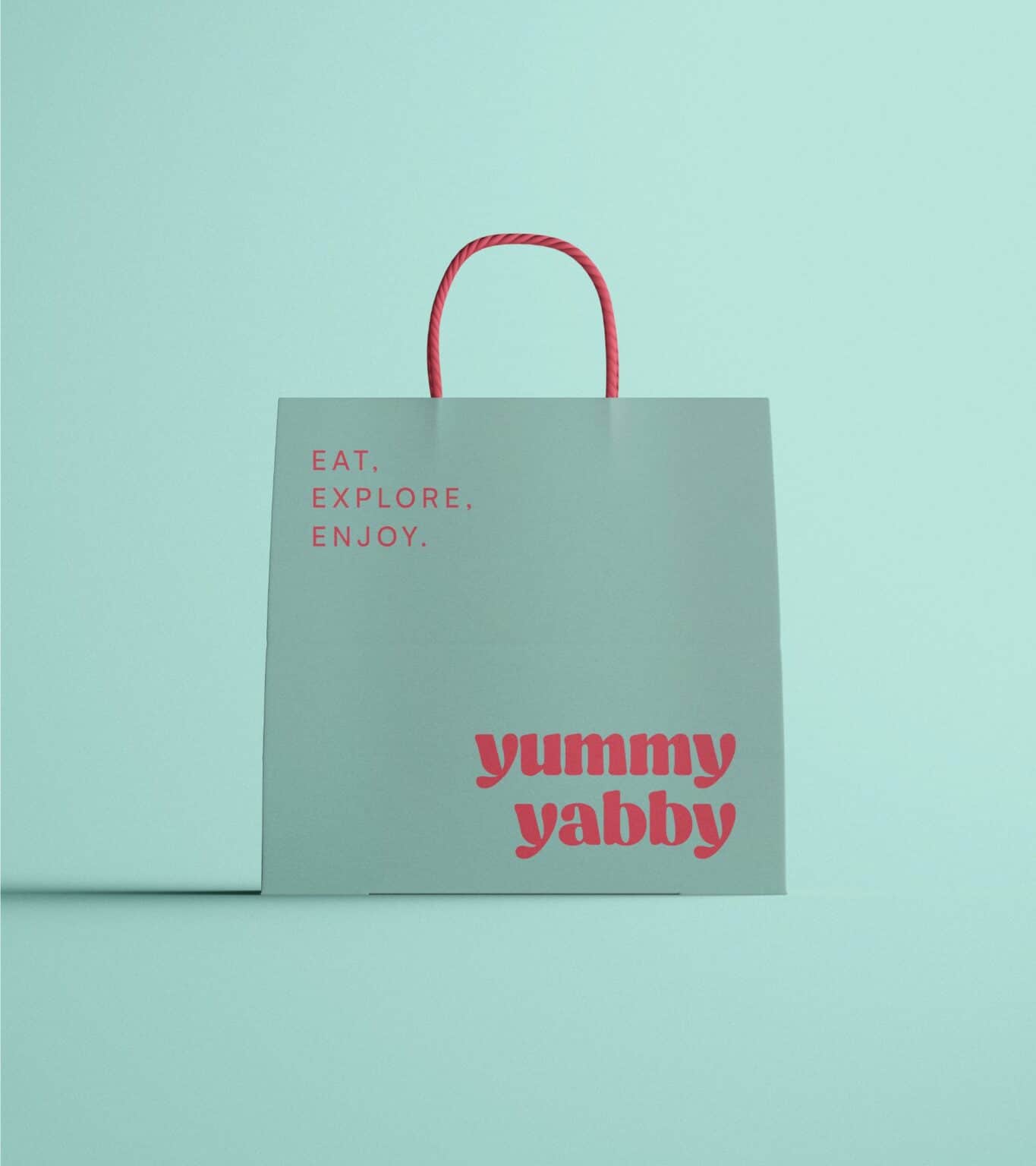 Bolsa de papel turquesa de Yummy Yabby con el logotipo en rosa