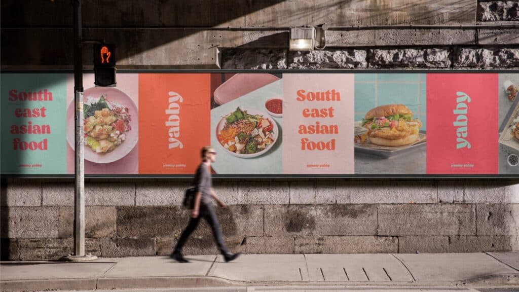 Carteles de Yummy Yabby en un muro de la calle, con platos del sudeste asiático y el lema South east asian food