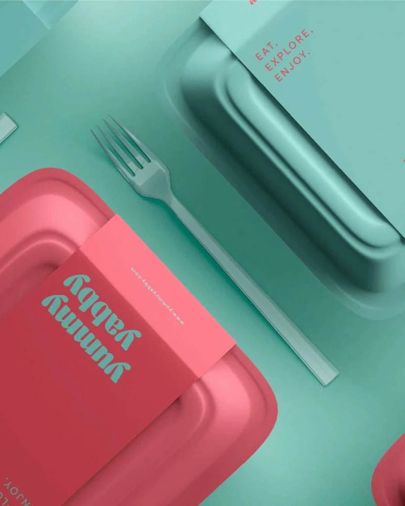 Yummy Yabby takeaway packaging in pink and turquoise, with branded sleeves and cutlery
