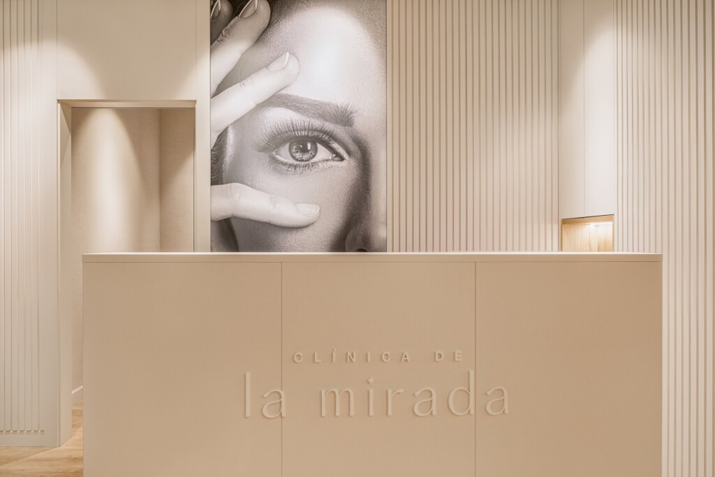 The reception desk with Clínica de la Mirada in relief, beneath the black-and-white portrait of a gaze