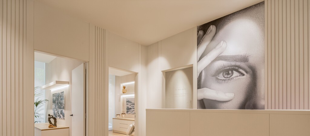 Reception at Clínica de la Mirada: the desk with the logo in relief beneath a large black-and-white portrait of a gaze