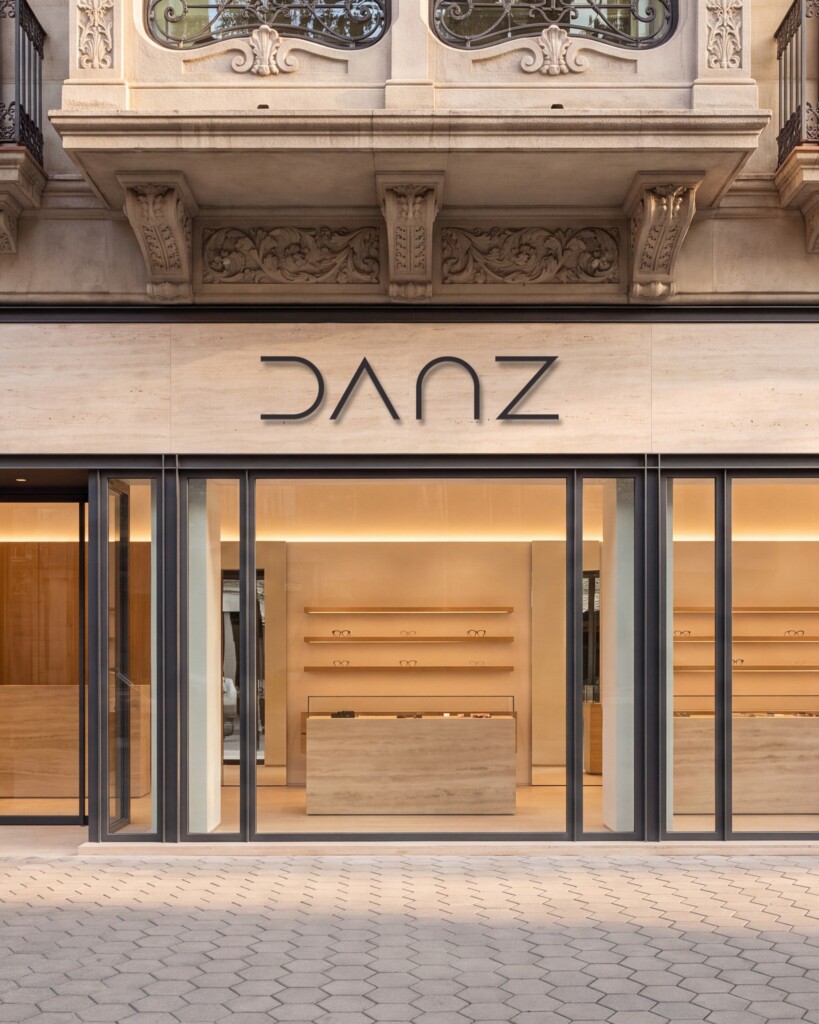 Recreación: fachada de una tienda de DANZ Barcelona con el logotipo en metal grafito sobre travertino