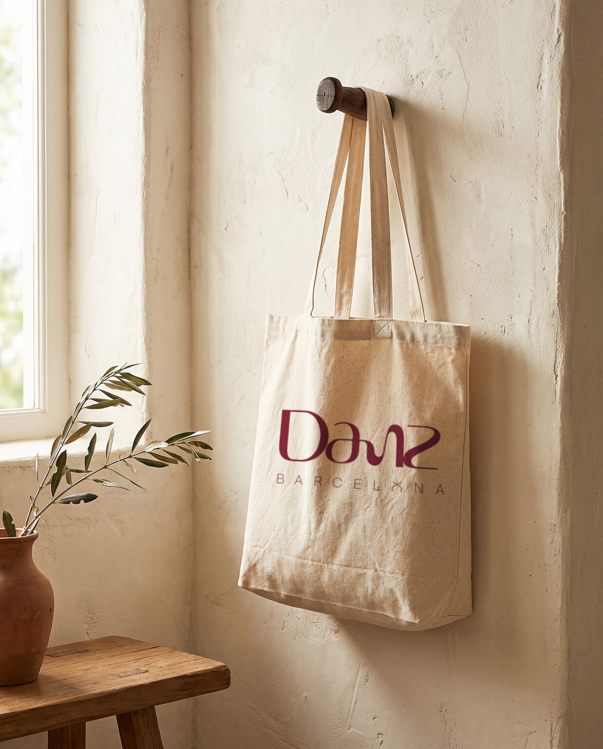 Recreación: bolsa de tela colgada en la pared con el logotipo de la línea «Ritmo» de DANZ estampado en burdeos