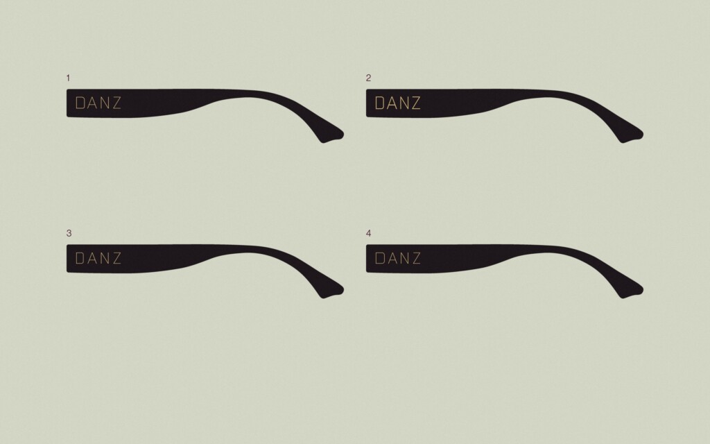 Prueba del logotipo de DANZ Barcelona en oro sobre cuatro varillas de gafa negras, a tamaño de producto