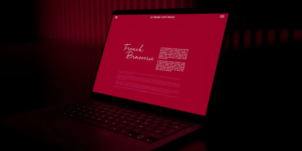 Recreación: la web de Le Grand Café Rouge abierta en un portátil sobre una mesa oscura, en la sección French Brasserie