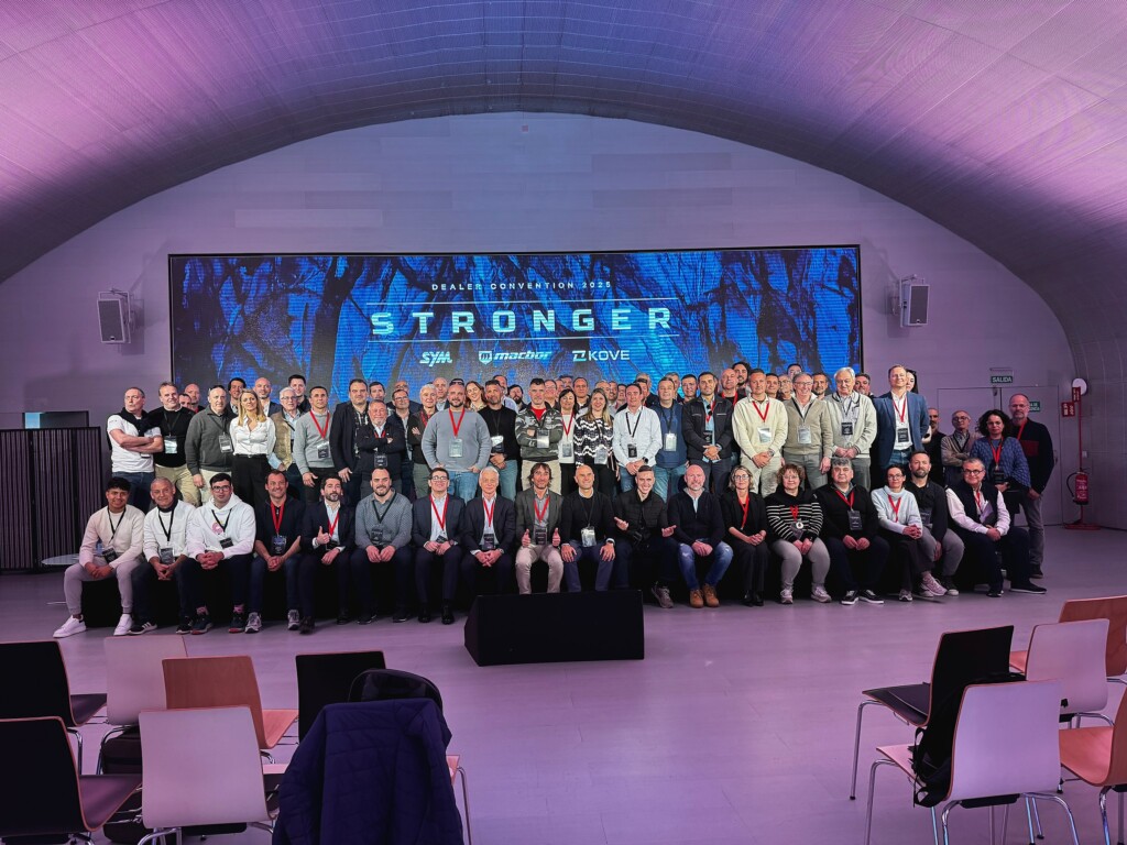 Foto de grupo de la red de concesionarios de SYM, Macbor y KOVE ante la pantalla «Stronger»